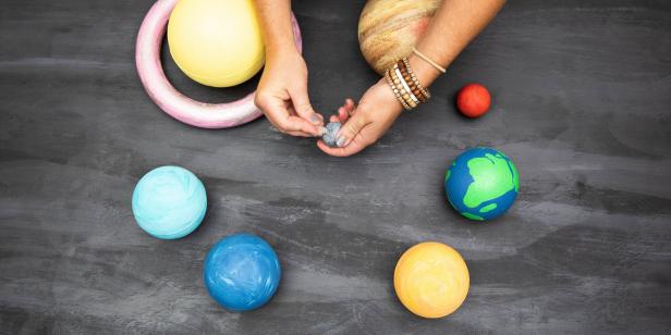 This solar system Halloween costume is comprised of DIY planets made from foam balls and paint. Plastic eyelets are screwed into the foam to suspend it from a wreath ring.
