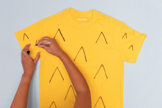 This yellow t-shirt is being transformed into a pineapple Halloween costume with a marker and some felt.
