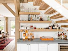 “This area, which is part of a large entertaining room in a house in North Haven, New York, used to be empty, so we had the idea to continue the bar cabinets from around the corner,” says designer Timothy Godbold. He maxed out wall space by varying the lengths of the reclaimed oak shelves, where bottles and glasses look fab shown off. Even the way they’re arranged (alternating bottles and glasses, plus a group on a tray) has style. 