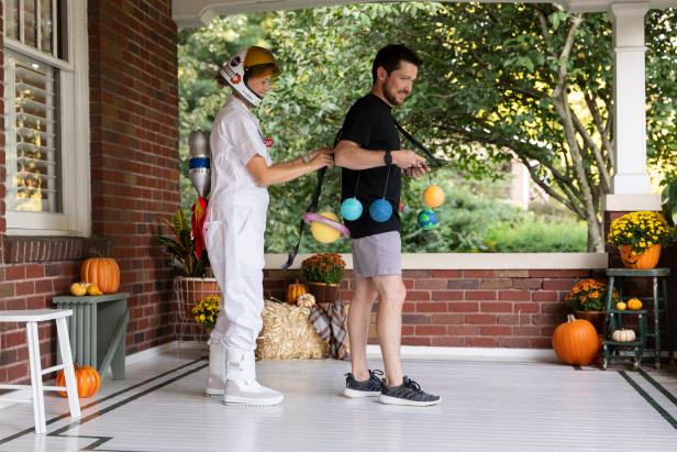 This solar system costume is comprised of foam balls painted to look like all the different planets making up the solar system. The foam balls are then hung from a large floral wreath ring that is attached to suspenders and worn with a black shirt.