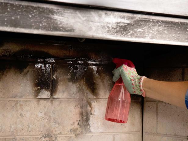 Lay out newspaper on the bottom of the firebox to catch debris and spray the walls down with equal parts vinegar and warm water to clean the bricks. Scrub with a brush and let air dry.