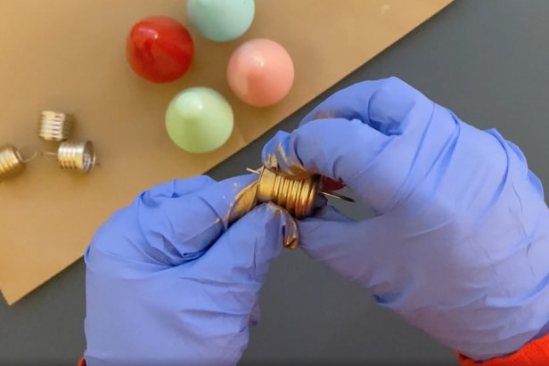 While the bulbs are drying, prepare the ornament tops. Tip: Wear rubber gloves to apply gilding wax with your fingertips. Apply an even layer of gold gilding wax around the ornament top to create a shimmer. Let them dry overnight.