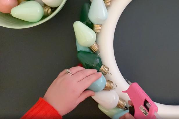Continue to add bulbs around the foam form. Then, secure the second row of bulbs by adding hot glue directly to the form and the first layer of bulbs. Continue adding bulb layers until the wreath is complete.