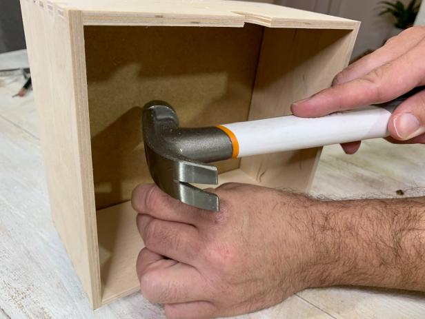 Lay the handle in place and insert the post of the rivet through the hole. The rivet should be large enough to pass through the wood. Carefully turn the drawer and position the cap on the rivet post. Position the rivet onto the anvil then tap with a hammer until secure. Repeat for all handles until each is attached.