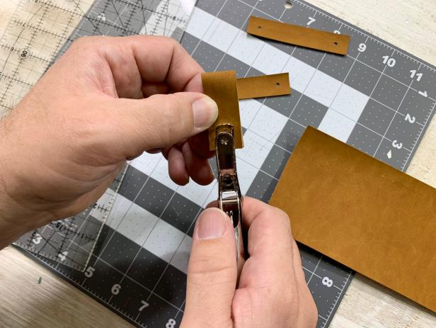 se a ruler and cutting mat to measure out 8 equal size pieces of faux leather. Cut each handle out using a rotary blade or pair of scissors. Fold each piece in half so that the ends meet. Using punch pilers, punch through both pieces about a  ½ inch from the edge.
