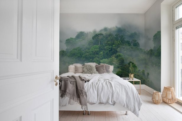 A white bedroom features a large bed and wallpaper with misty trees.