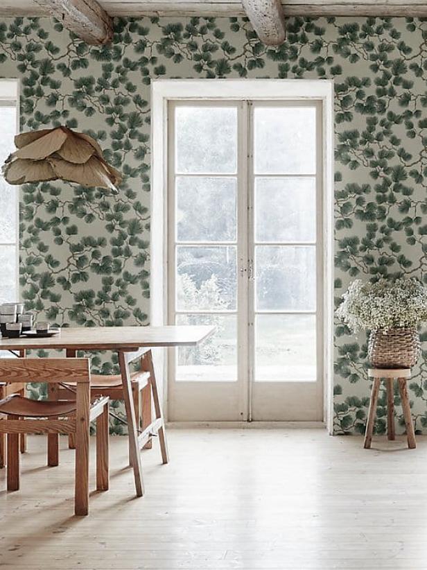 Pale dining room features natural wood and bough-printed wallpaper.
