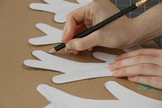 Trace the tree pattern onto a large piece of cardboard and cut it out with a craft knife. You may want to use scissors to get a smoother rounded end on each of the branches. Repeat this to make six Christmas tree halves.