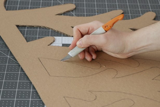 Trace the tree pattern onto a large piece of cardboard and cut it out with a craft knife. You may want to use scissors to get a smoother rounded end on each of the branches. Repeat this to make six Christmas tree halves.