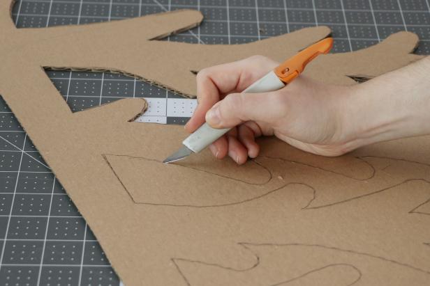 Trace the tree pattern onto a large piece of cardboard and cut it out with a craft knife. You may want to use scissors to get a smoother rounded end on each of the branches. Repeat this to make six Christmas tree halves.