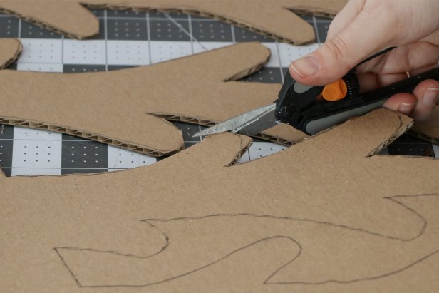 Trace the tree pattern onto a large piece of cardboard and cut it out with a craft knife. You may want to use scissors to get a smoother rounded end on each of the branches. Repeat this to make six Christmas tree halves.