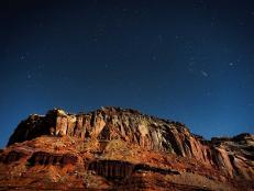 Night sky and stars over rock formation.
