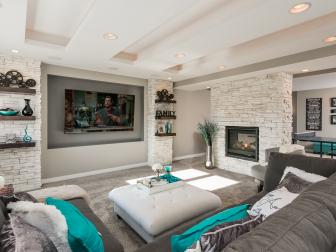A stacked stone fireplace, a tray ceiling and bright color palette make this basement living area a family-friendly space made for relaxing. 
