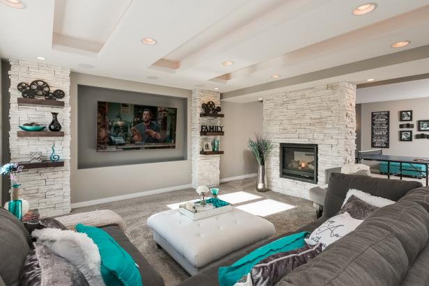 A stacked stone fireplace, a tray ceiling and bright color palette make this basement living area a family-friendly space made for relaxing. 