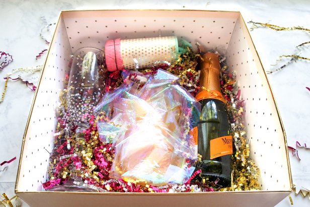 HGTV Handmade’s A.V. Perkins shares a step-by-step guide to make a New Year’s Eve gift box filled with festive crafts to send to friends near and far. To make your own, you will need shiny gift wrap or Mylar paper, scissors, clear tape and a 6' piece of string or yarn.