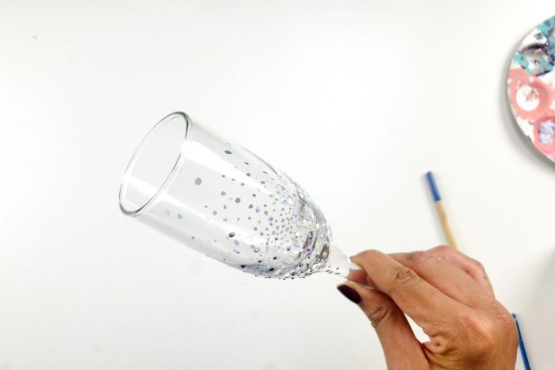 Hand Holds Painted Glass Champagne Flute With Color Bubbles on Bottom