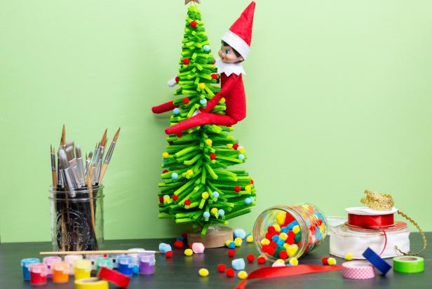 A toy self sits on a miniature faux Christmas tree.