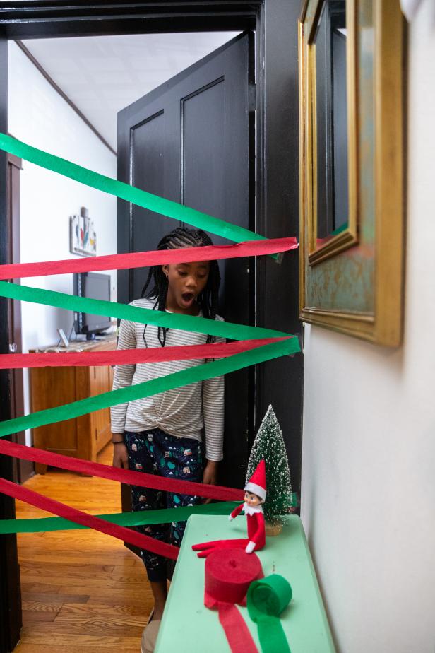 A child stands in a doorway with red and green streamers across it.