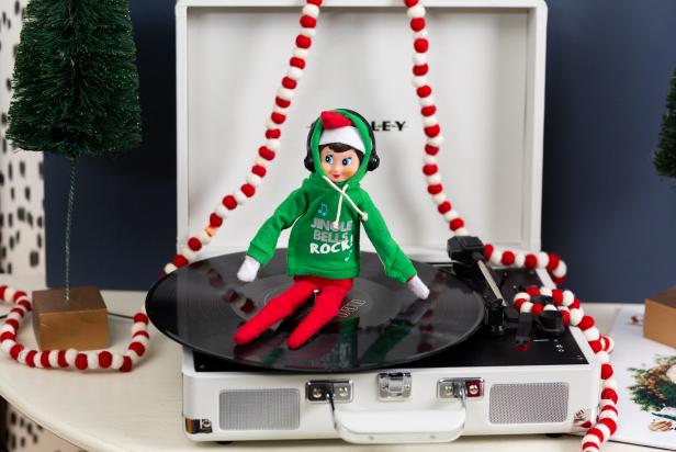A toy elf dressed as a DJ sits on a record player.