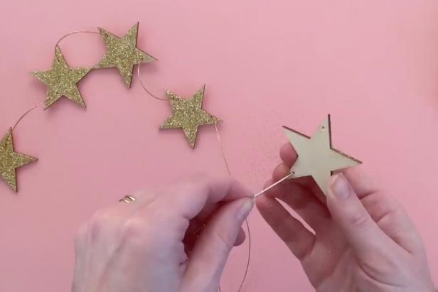 Thread the gold string through the two holes on the glitter star using an embroidery needle.