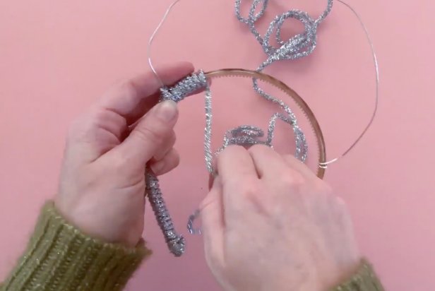 Start by measuring jewelry wire around the plastic headband. Next, cut the cord and wrap the ends of the wire tightly around the middle part of the plastic headband. Then use a low-temp hot glue gun to add a bead of glue to the bottoms of the plastic headband. Now wrap the glitter string starting at the ends and wrapping tightly up the headband. Once to the other end, add a bead of glue from a low-temp hot glue gun to secure ends.