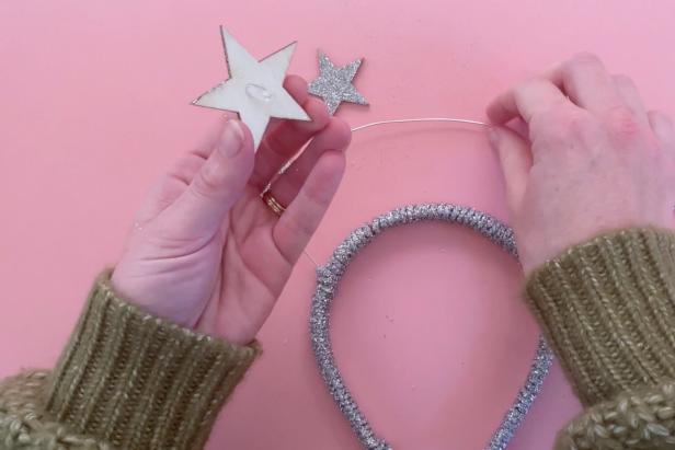 Arrange the wooden stars in a pattern that fits the plastic headband. Next, paint a coat of decoupage glue to the star. Shake a generous amount of glitter onto the star, then let dry. Once dry, add a dot of glue from a low-temp hot glue gun to the back of each wooden star and affix it to the jewelry wire on the headband. Once secure and all the stars are placed on the headband, add another coat of decoupage glue to the back and shake on a generous amount of glitter. Leave the headband to dry for several hours.