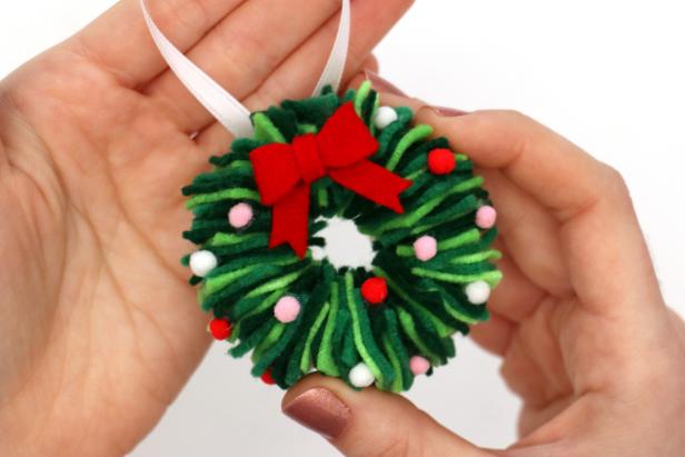 Glue the bow to the wreath, along with a piece of ribbon as a hanger. Glue mini pom-poms all over the wreath as a finishing touch.