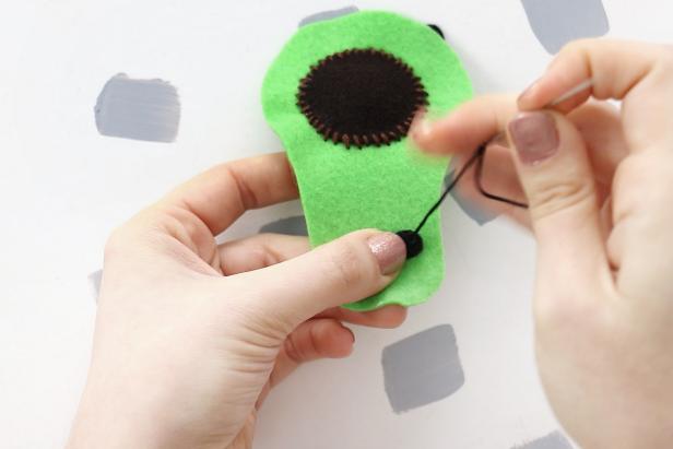 Sew the eyes on the avocado with black thread and the cheeks with pink thread. Add reflections in the eyes with a small piece of white thread as well as a smile from black thread.