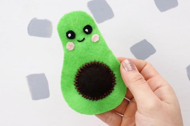 Sew the eyes on the avocado with black thread and the cheeks with pink thread. Add reflections in the eyes with a small piece of white thread as well as a smile from black thread