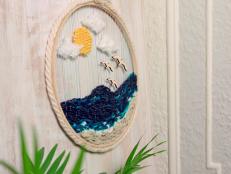 Embroidery hoop and yarn wreath with beach scene hangs on wall