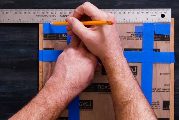 Use a ruler to center the acrylic on the wood. Then, wrap painters tape horizontally and vertically around both pieces to hold in place. Measure ½ inch from each corner and mark with a pencil.