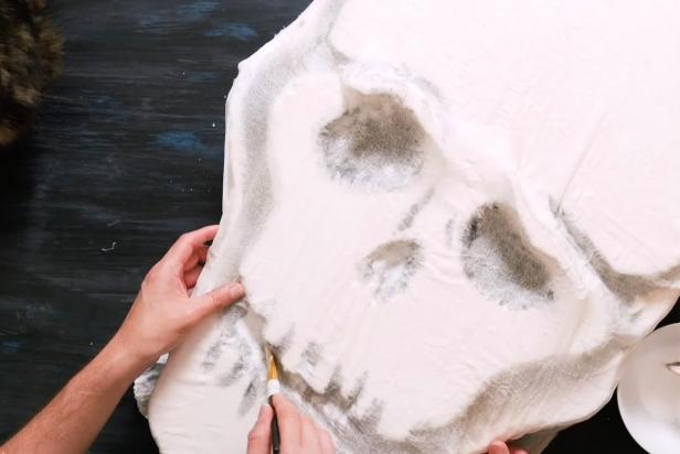 Soak a large piece of sheer fabric that fits over the entire skull in a bowl of watered down decoupage medium. Squeeze and ring out the fabric. Then open the fabric and lay over the entire skull. Smooth out fabric around the skull. Press into the eyes to create sockets and wrap the fabric around the back to let dry.