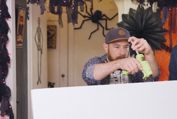 Man Using Hot Glue Gun To Apply Glue to Seam of Styrofoam Board