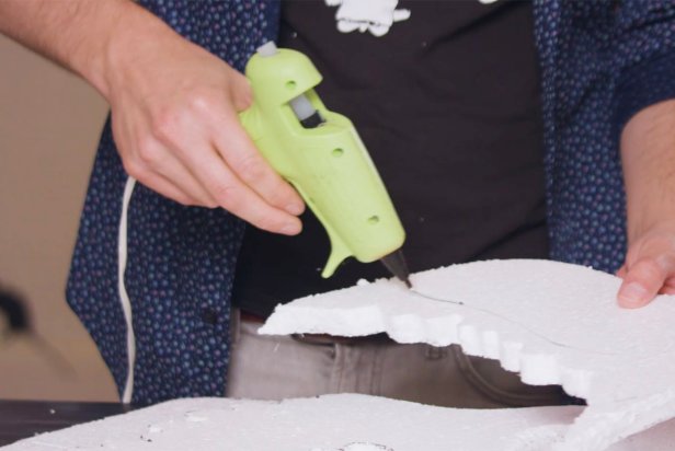 Hand Using Low Temp Glue Gun To Glue Jaw To Larger Skull Piece