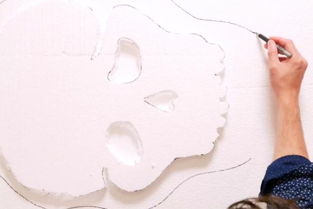 Lay the pre-cut skull on top of the second piece of styrofoam. Use a marker to trace out eye holes and around the outside of the skull leaving a three-inch border to create dimension.