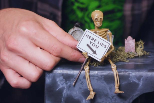 Finish by decorating the top of the box with gravestone miniatures, moss and a skeleton to create a spooky and inviting scene.