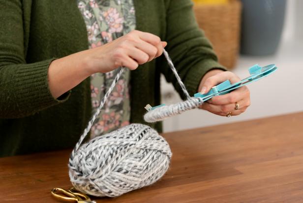 Start by lining up the two sides of your pom-pom maker and begin wrapping the yarn. To get a really even result, be sure to wrap back-and-forth and layer-by-layer across the sides of your pom-pom maker.