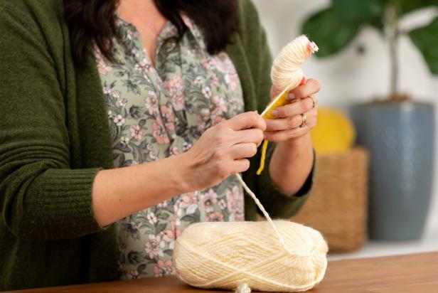 Use about half of the first color on one side. Continue wrapping until the side with one color is full and nearly coming off the pom-pom maker. Cut the yarn from the skein. Next, move to the other color of yarn and repeat steps above. Reserve a foot-long piece of yarn for later.