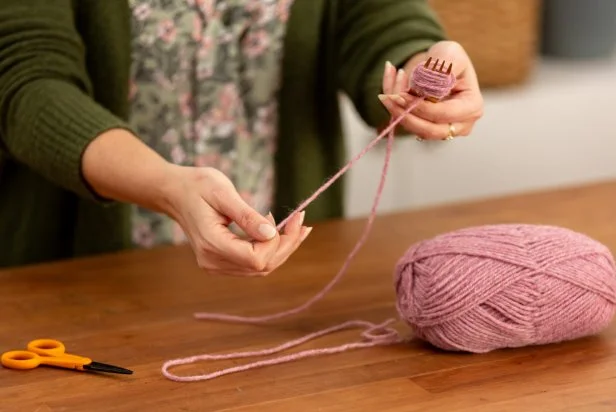 Once wrapped, cut the yarn using scissors. Then, take the pre-cut piece of yarn and push it through the center tine of the fork.