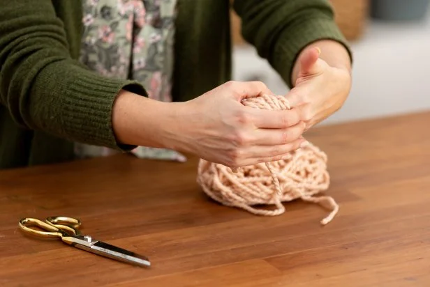 To keep the pom-pom fluffy, be sure not to wrap the yard too tightly around your hand. Then, gently slide the pom-pom off your hand.