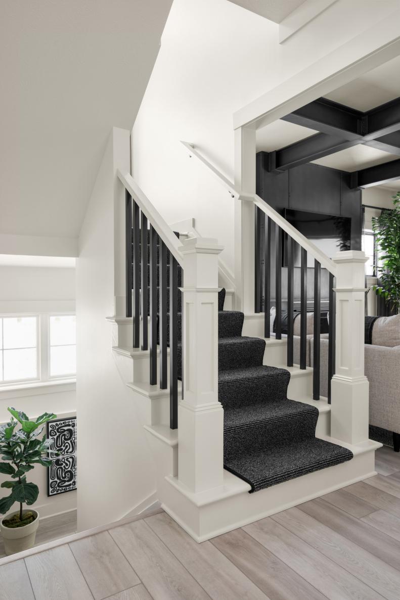 Beautiful White Staircase Accented With Black Carpet and Balusters