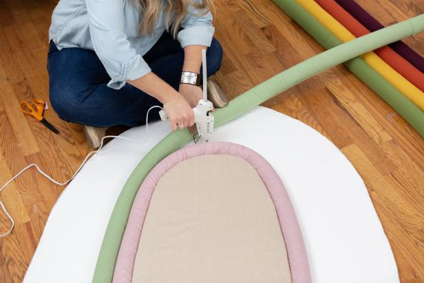 Using a lo-temp hot glue gun and starting with the shortest piece, glue the rainbow bands together and to the foam board. Make sure that the fabric seam is hidden and glued to the back.