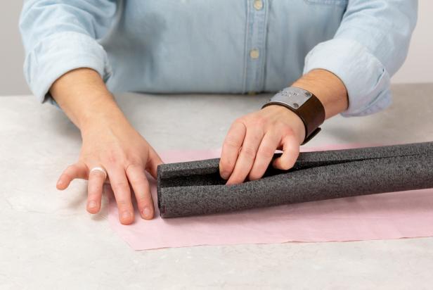 Using a lo-temp hot glue gun, wrap the fabric around the pipe insulation and glue to attach at the seam. Make sure to use a lo-temp hot glue as anything hotter will melt the foam.