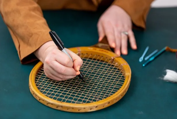 Using a permanent marker, mark the center points of your design on the tennis racket. The yarn will cover up the markings.