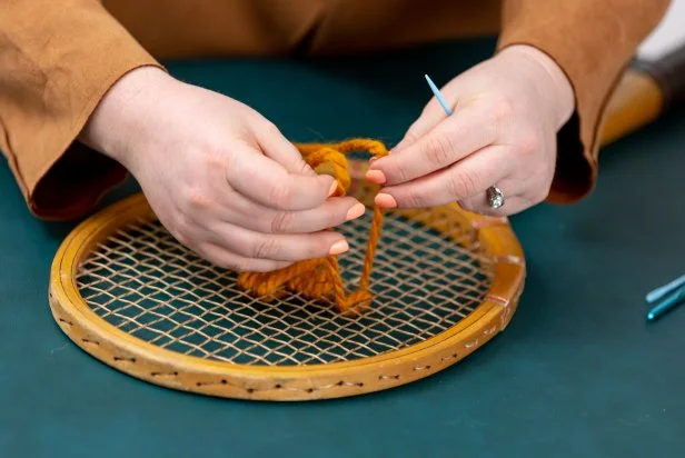 Thread the yarn through the squares to weave your design. Once you get started on a section, tie off the end to make the design tight.