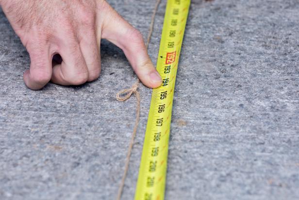 This string has been tied at a knot and a measuring tape is being used to measure the distance to the knotted portion of the string.