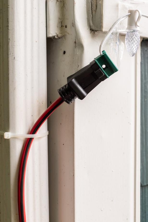 This outdoor extension cord is held in place with a zip tie to keep it form pulling the Christmas lights off of the house. The Christmas string lights are custom cut from a bulk spool of string lights.