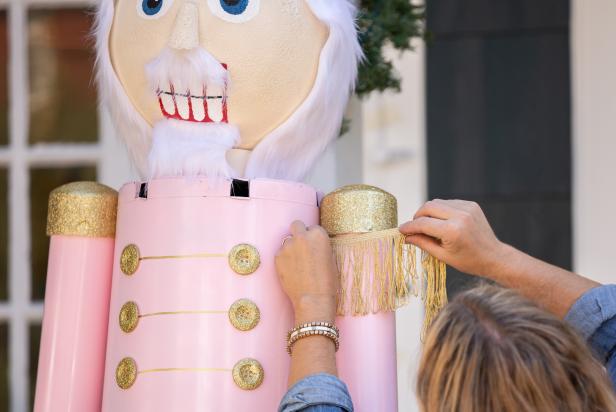 Fringe is added to the shoulder of this giant nutcracker Christmas decoration that is made out of PVC pipes and plastic planters.