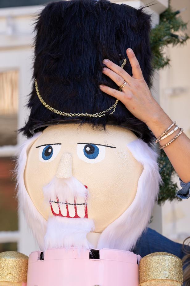 A hat made from a planter and faux fur is placed atop the head of a DIY giant nutcracker Christmas decoration.