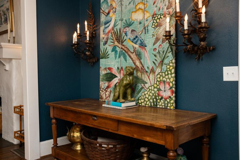 Wooden Entry Table With Antique Sconces and Tropical Bird Art Above